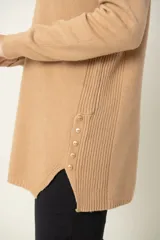 Buzo camel de viscosa y poliamida, con cuello redondo, corte holgado, tajos laterales y botones decorativos.