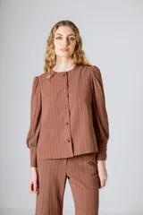 Chaqueta marrón a rayas verticales, con cuello redondo, cierre frontal con botones y mangas largas abullonadas con puños abotonados.