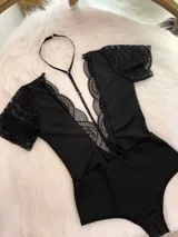 Body entallado de lycra color negro, con escote pronunciado decorado con encaje y microtul. Presenta mangas cortas de encaje y un collarín regulable desmontable integrado al diseño.