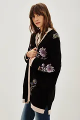 Cardigan negro de punto con bordados florales y aplicaciones de lentejuelas. Presenta terminaciones en tejido acanalado de color beige en los puños, el ruedo y a lo largo de la apertura frontal.