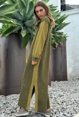 Vestido largo de punto en color verde oliva, con diseño de paneles en dos tonos de verde, mangas largas con textura perforada y tajos laterales en el ruedo.