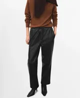 Pantalón negro de cuero sintético, de tiro medio con cintura elástica ajustable mediante cordón y diseño de pernera recta.