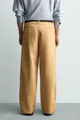 Pantalón chino straight fit de corte recto y holgado, color tostado, con pliegues frontales en la cintura, bolsillos laterales y cierre con cremallera y botón.