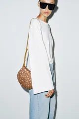 Bolso bandolera de diseño estructurado, con cuerpo en estampado animal tipo cervatillo en tonos marrón y blanco. Cuenta con solapa curva, cierre de botón imantado, bolsillo interior con cremallera y correa larga ajustable.