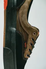Championes Vans modelo Skate Era Wafflecup, con diseño bicolor en negro y marrón. Presentan una silueta clásica de skate con suela WaffleCup que combina durabilidad y flexibilidad, cordones negros y detalles en color naranja en la lengüeta, plantilla y suela.