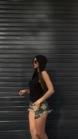 Short de jean con estampado de camuflaje en tonos verde, marrón y beige, con terminaciones desflecadas.