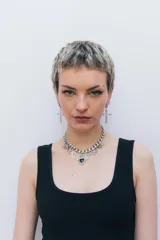 Par de aros colgantes plateados con forma de cruz ornamentada y cierre tipo argolla.