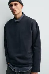 Sudadera de corte relajado confeccionada en algodón compacto con interior de rizo. Presenta cuello redondo acabado en rib, manga larga y bordes irregulares enrollados.