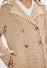 Tapado largo de tejido de punto color beige con diseño a cuadros sutil. Presenta cuello solapa, cierre frontal con botones y bolsillos laterales.