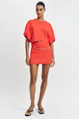 Falda corta de punto con cintura elástica y diseño en evasé de color rojo.