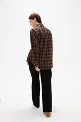 Camisa de poliéster con estampado a cuadros, cuello camisero, cierre frontal con botones y detalle de lazo ajustable en la cintura.