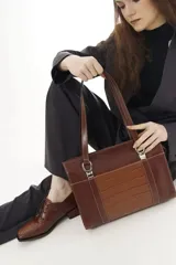 Cartera tipo shopper de cuero genuino marrón con panel central de textura símil cocodrilo y herrajes metálicos plateados.