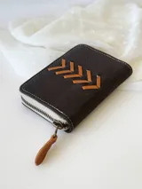 Billetera pequeña de cuero negro con cierre metálico y diseño de espiga en cuero color tostado.