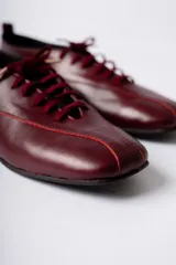 Zapato acordonado de cuero color negro, de diseño minimalista con punta cuadrada y silueta moderna.