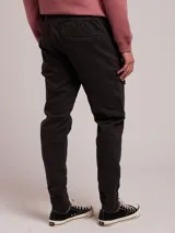 Pantalon cargo de sarga color negro, con cintura elástica ajustable mediante cordón, bolsillos laterales tipo cargo y puños elásticos en los tobillos.