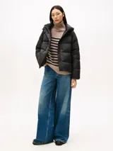 Campera acolchada tipo puffer de Tommy Hilfiger, color negro, con relleno de plumón, capucha fija, cierre frontal con cremallera oculta y botones a presión, y logo tonal bordado en el pecho.