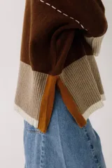 Buzo de lana color beige con bloques de color ocre y bordó en mangas y ruedo. Presenta un bolsillo pequeño en el pecho y costuras decorativas en color bordó.