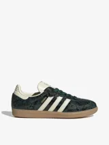 Zapatillas Adidas Samba OG con exterior de piel con estampado de piel de serpiente en tonos verde oscuro y negro. Cuentan con las 3 Franjas dentadas en color blanco crema, cordones verde oscuro, revestimientos en color crema claro y puntera en T reforzada. La suela es de caucho color caramelo.