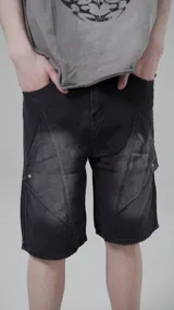 Bermuda de denim con diseño de paneles geométricos y efecto lavado desgastado. Presenta un corte regular fit con detalles de remaches metálicos en los laterales.