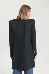 Saco largo negro de lino con acceso cruzado, silueta recta y hombreras altas. Tiene botones dorados.