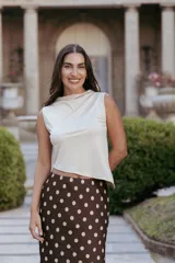 Top sin mangas de cuello bote, confeccionado en tela elastizada con diseño asimétrico en el ruedo.
