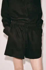 Shorts de lino de tiro medio, color rosado, con cintura elástica ajustable mediante cordones y bolsillos delanteros.