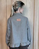 Sobrecamisa de pana color marrón oscuro, con cuello camisero, cierre frontal de botones y detalle de volado en el ruedo. Presenta mangas largas con puños y bolsillos frontales aplicados.