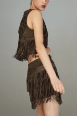Top corto sin mangas de cuello redondo, confeccionado en tejido tipo gamuza con múltiples capas de flecos decorados con aplicaciones de brillos. Cuenta con cierre posterior oculto.