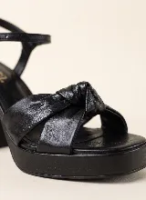 Sandalia de taco alto ancho con plataforma delantera y diseño elegante y sofisticado. Presenta una capellada con tiras anchas y detalle de nudo central. Incorpora pulsera ajustable con hebilla en el tobillo.