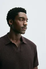 Polo de manga corta color marrón oscuro, confeccionado en tejido waffle de algodón, con cuello solapa y abertura frontal.