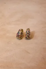 Aros tipo argolla con base metálica dorada e incrustaciones de cristales negros en toda su superficie frontal.