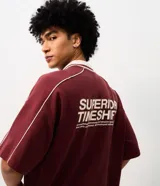 Remera de punto color bordó con ribetes blancos en los hombros y cuello polo, de corte holgado y manga corta. Cuenta con un diseño estampado en la espalda con texto en tonos claros.