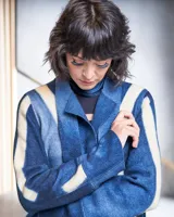 Tapado largo de lana merino afieltrada, color fucsia con diseño tie-dye artesanal en tonos claros y crudos. Tiene cuello que se prolonga a modo de cinto, aberturas laterales y bolsillos.