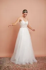 Vestido largo blanco de alta costura, con corset estructurado de tirantes finos con apliques florales y falda amplia de tul con brillo.