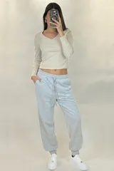 Pantalon deportivo tipo babucha de color beige, con cintura elástica ajustable mediante cordón y puños elásticos en los tobillos.