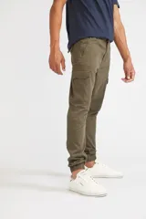 Pantalón cargo de corte slim, color verde oliva, con bolsillos laterales tipo cargo, cierre frontal con botón y puños elásticos en los tobillos.