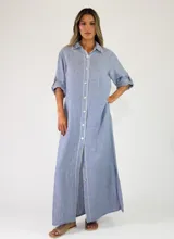 Vestido largo estilo camisero de lino color azul, con mangas largas arremangables, cuello camisero y cierre frontal completo con botones.