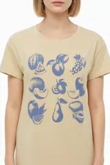 Remera blanca de manga corta y cuello redondo, con diseño estampado en el frente que simula un sello postal con palmeras y la inscripción 'la paloma'.