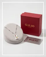 Collar de acero con cadena de eslabones y pequeñas esferas metálicas intercaladas. Presenta un dije rectangular de superficie texturizada con incrustaciones de circonias multicolor.