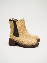 Bota tipo chelsea de cuero vacuno en color rojo con estampado floral grabado en negro. Presenta paneles laterales elásticos, suela de plataforma y taco cuadrado en color negro.