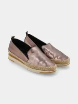 Slip-on de cuero color cobre con acabado metalizado y efecto craquelado, con detalles de yute trenzado alrededor de la base y suela deportiva bicolor.