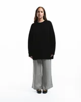 Sweater negro de punto con cuello redondo y corte holgado. Diseño con motivo de zurcido en la manga izquierda.