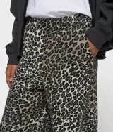 Pantalón deportivo ancho de corte regular con estampado de leopardo, confeccionado en suave algodón orgánico con certificación GOTS. Cuenta con cintura elástica con trabillas para cinturón, bolsillos laterales inclinados y el número '10' bordado debajo del bolsillo izquierdo.