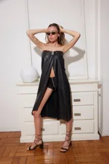 Vestido negro de cuero sintético, strapless, con abertura frontal y detalle metálico en el centro.