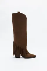 Bota texana de caña alta confeccionada en gamuza color marrón, con detalle de flecos laterales, punta afinada y taco medio.