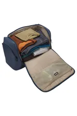 Bolso tipo duffel de la marca Thule, color azul oscuro, con diseño estructurado y compartimentos múltiples. Cuenta con asas reforzadas, correa de hombro ajustable y desmontable, cierre principal con doble cremallera y bolsillos laterales y frontales organizadores.
