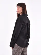 Camisa negra de manga larga con cuello clásico y cierre cruzado con botones.