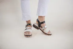 Sandalias de cuero color blanco y plateado, con tiras anchas y ajuste con hebilla. Suela track color caramelo.