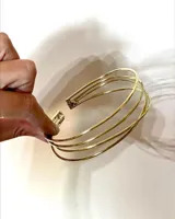 Brazalete rígido dorado de bronce con cuatro aros paralelos.