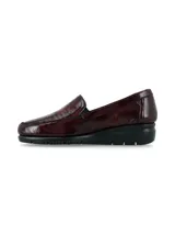 Zapato mocasín slip-on de cuero charol color bordó, con suela anatómica negra en contraste y diseño atemporal.